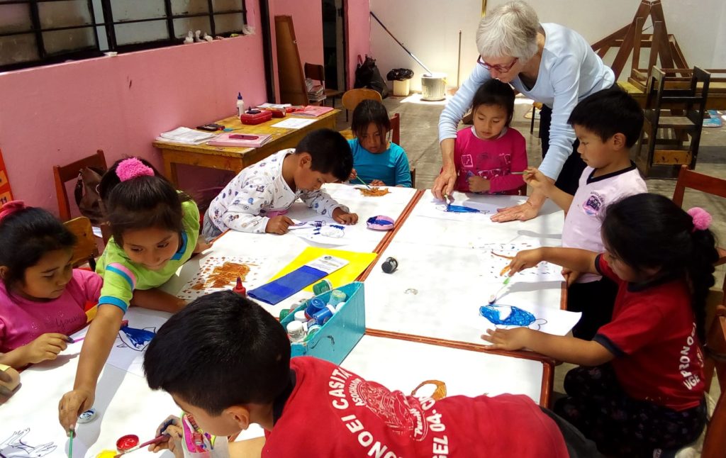 Atelier créatif : enfants des casitas et bénévole autour d'une grande table de peinture